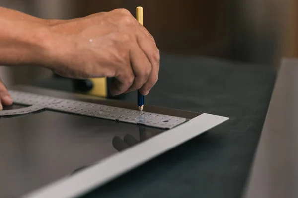 Homem desenhando uma linha usando um quadrado em uma superfície em uma oficina. — Fotografia de Stock