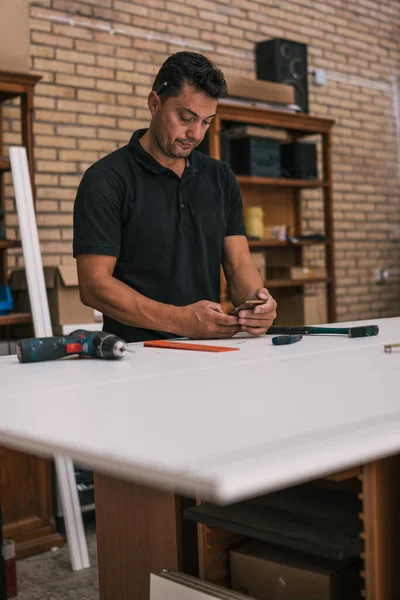 Hombre adulto usando un teléfono celular en un taller —  Fotos de Stock