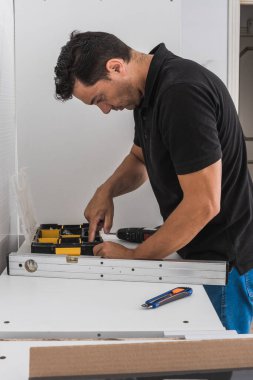 Mutfak ünitesini monte etmek için alet kutusunda çivi arayan bir adam.