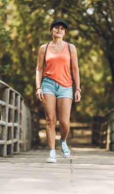 Yaz kıyafetleri içinde, tahta bir patikada yürüyen bir kadın.