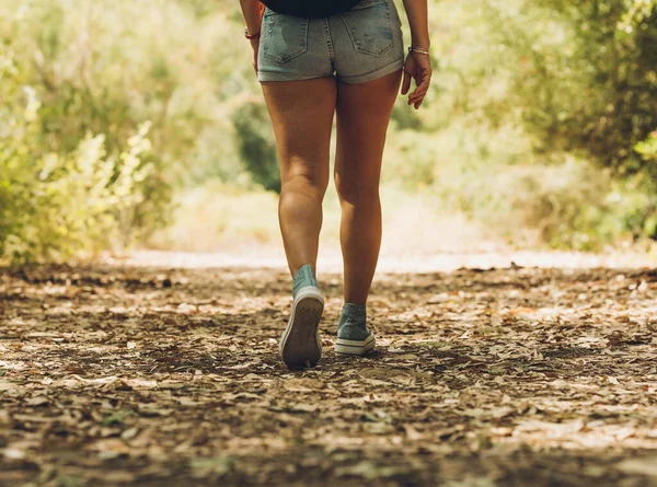 Legs of a woman in shorts walking across a the forest