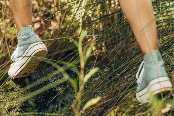 Detail of a womans feet jumping over wet rocks in a field — Stock Photo, Image