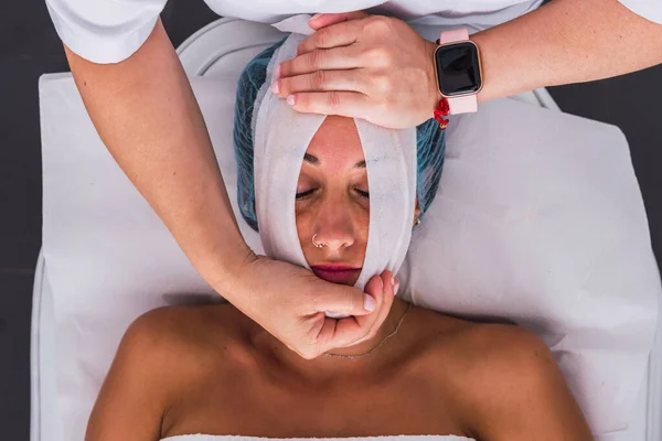 Cosmetoloog toepassen van een huidverzorging behandeling met gaas voor volwassen vrouw in de schoonheidssalon — Stockfoto