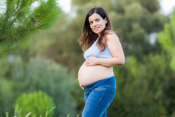 Porträtt av en gravid kvinna stående i en park — Stockfoto