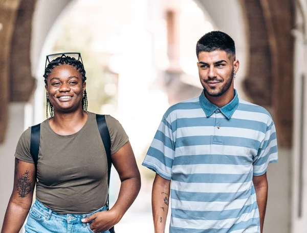 两个不同种族的年轻人在穿过一座城市时微笑着 — 图库照片