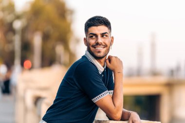 Modern elbiseli bir adam sokakta gülümserken dikkati dağılmış görünüyor.