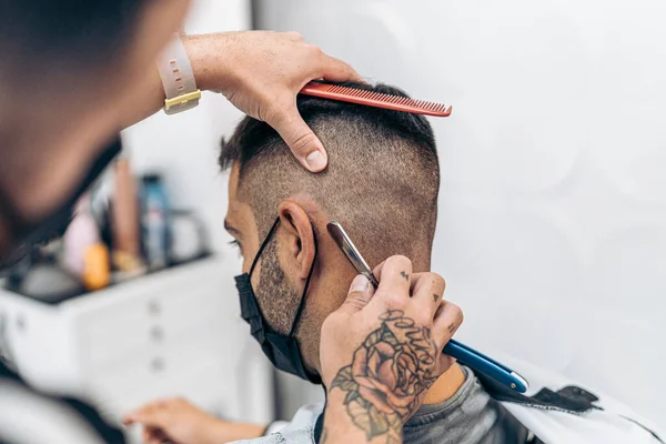 Barbeiro raspando o cabelo de um homem usando uma navalha em uma barbearia — Fotografia de Stock