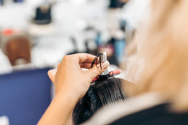 Cabeleireiro usando um rolo para enrolar um cabelo clientes — Fotografia de Stock