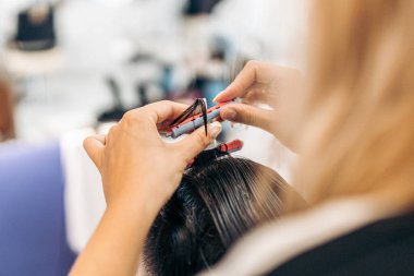 Müşterilerin saçlarını kıvırmak için bigudi kullanan bir kuaförün elleri.