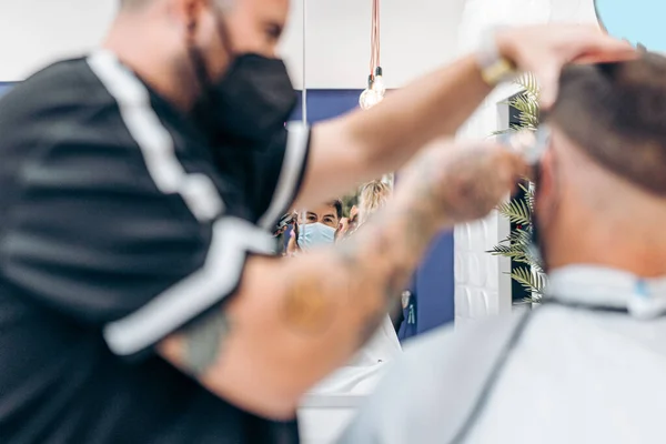 Reflexão em um espelho de um cliente com máscara em uma barbearia — Fotografia de Stock