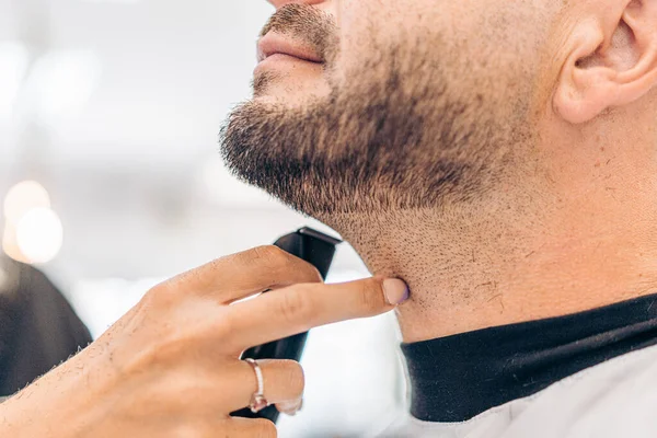 Finger of a woman pointing a shaved beard of a caucasian adult man in a salon — Stock Photo, Image