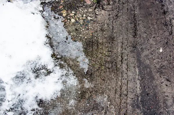 Traços de pneus na areia. Rastreamentos de rodas na terra. Faixas de pneus escuros fundo com neve e água. Rastreio de rodas no chão lamacento. O traço de um pneu na areia — Fotografia de Stock