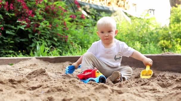 Schattig klein kind dat plezier heeft met zand en kleurrijk speelgoed in het park, op een goede zomerzondag in de speeltuin — Stockvideo