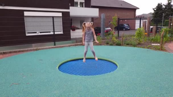 Glückliches Kindermädchen beim Trampolinspringen auf einem Kinderspielplatz — Stockvideo