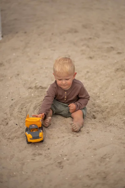 可爱的小宝宝在沙滩上玩玩具车 — 图库照片