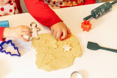 Çocuklar bayram pişirme seansı sırasında hamurdan kurabiye şekilleri kesiyorlar. Renkli kesiciler neşeli bir atmosferde çeşitli şenlik tasarımları yapmak için kullanılır..