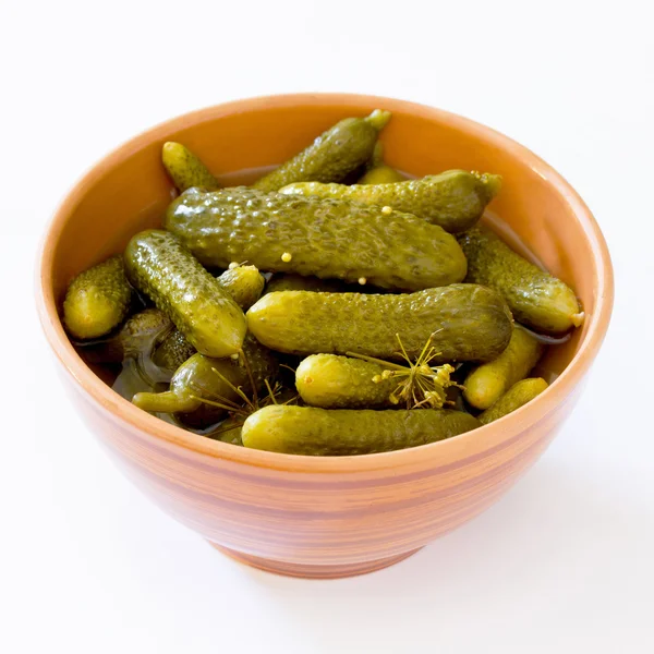 Concombres marinés cornichons dans une tasse en céramique sur un fond blanc — Photo