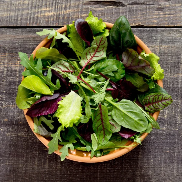 Fresh green mixed salad in a bowl on a dark wooden table
