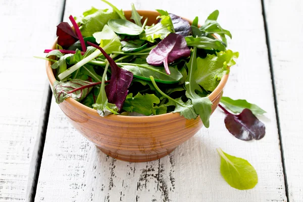 Gemischter Salat in einer Keramikschüssel auf einem weißen Holztisch — Stockfoto