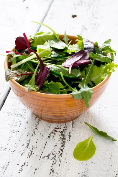 Frischer grüner gemischter Salat in einer Schüssel auf einem weißen Holztisch — Stockfoto