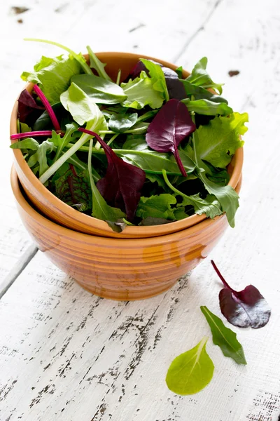 Gemischter Salat in einer Keramikschüssel auf einem weißen Holztisch — Stockfoto