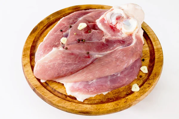 Pezzo di carne cruda su una tavola di legno con aglio e pepe — Foto Stock