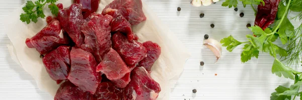 Una carne fresca cruda, especias y verduras en un fondo de madera ligera — Foto de Stock