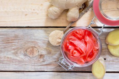 Zencefil kökü ve ahşap bir masa üzerinde zencefil turşusu dilimleri, üst 