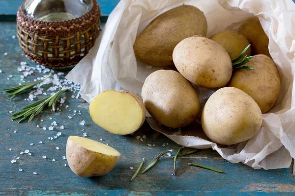 Colha novas batatas e galhos alecrim em um vintage de madeira de volta — Fotografia de Stock