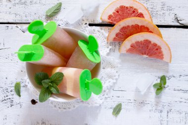 Beyaz ahşap backgrou üzerinde bir greyfurt ile lezzetli meyve buz