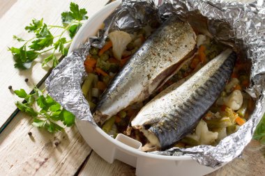 Ahşap bir masa, bir o folyoyu sebzeli balık pişmiş lezzetli