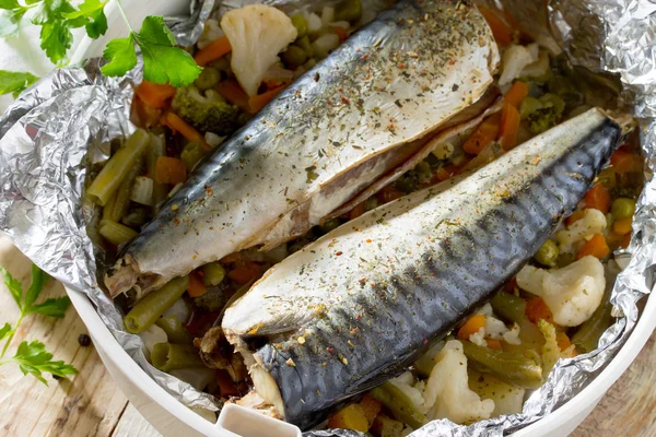 Leckeren gebackenen Fisch mit Gemüse in Folie auf einem Holztisch, — Stockfoto