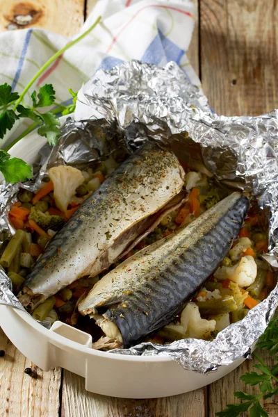 Вкусная запеченная рыба с овощами в фольге на деревянном столе, — стоковое фото