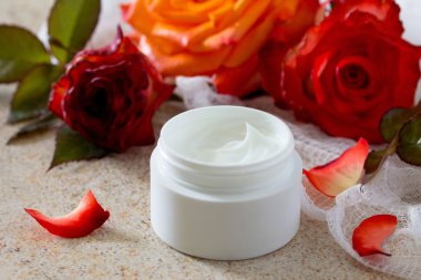 Kahverengi taş fone- güzellik salonu üzerinde gül ile yüz kremi.