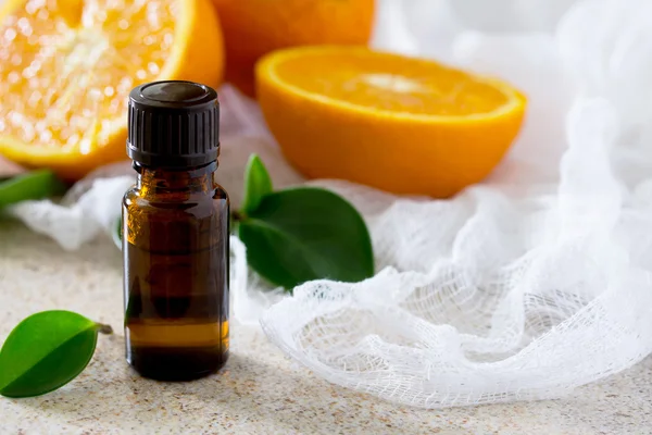 Bottle of orange essential oil for aromatherapy on a brown stone