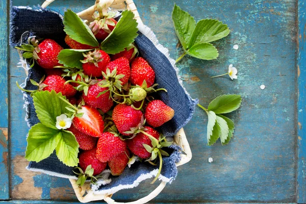 Oogst van de verse rijpe aardbeien in een rieten mand op oude woo — Stockfoto