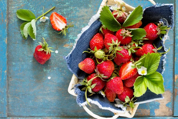 Oogst van de verse rijpe aardbeien in een rieten mand op oude woo — Stockfoto