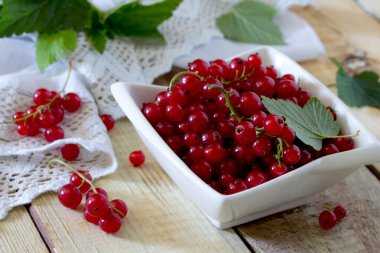 Olgun kırmızı kuş üzümü çilek seçmeli ahşap bir masa üzerinde bir kasede 