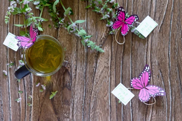 Nane çayı bir bardak arka plan dekorasyon kağıt kelebekler. — Stok fotoğraf