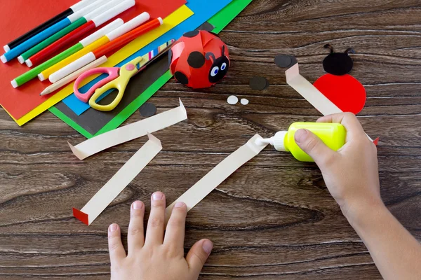 The child holds a paper strip and apply the adhesive. The child — Stock Photo, Image