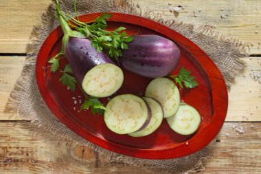 Taze otlar, tuz ve sebze ile ahşap bir masa üzerinde patlıcan 