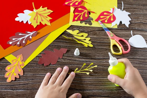 Autumn colored paper leaves on the wooden background. Child be g