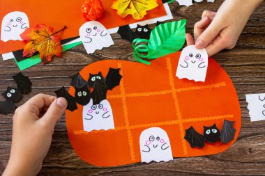 Ahşap bir masada Cadılar Bayramı balkabağı şeklinde komik bir kağıt oyuncak. Çocuk sanat projeleri, el sanatları, çocuklar için eğlenceli aktiviteler.