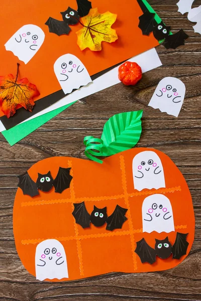 Halloween concept funny paper toy in the shape of a pumpkin. Childrens art project, crafts, fun activities for kids.