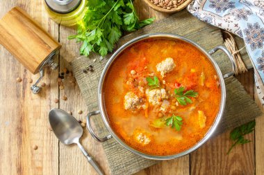 Köfteli domates mercimek çorbası ve ahşap bir masada sebze. Üst görünüm düz arkaplan.