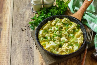 Diyet kahvaltı ya da sağlıklı öğle yemeği. Kırsal ahşap masada, dökme demir bir tavada karnabahar ile yumurta omleti. Boşluğu kopyala.