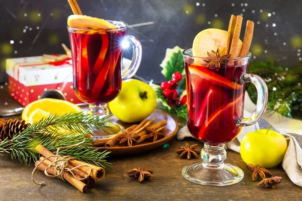 Mulled wine in glass mug with spices on rustic table. Winter Christmas hot drink with orange, apple and spices.