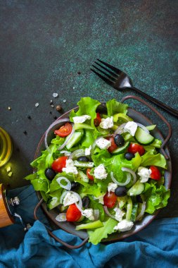 Sağlıklı diyet yemekleri. Yunan peynirli salata, salatalık, domates, tatlı biber, marul, kırmızı soğan ve zeytinyağlı zeytin. En üstteki düz yerde. Boşluğu kopyala.