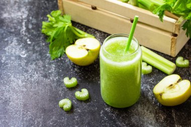 Sağlıklı beslenme ve beslenme, vegan, alkali, vejetaryen konsepti. Koyu taştan bir tezgahta elmalı ve kerevizli yeşil smoothie. Boşluğu kopyala. 