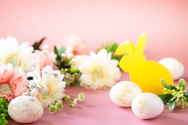 Easter floral background. Spring flowers gerbera with easter eggs on pink background. Copy space.